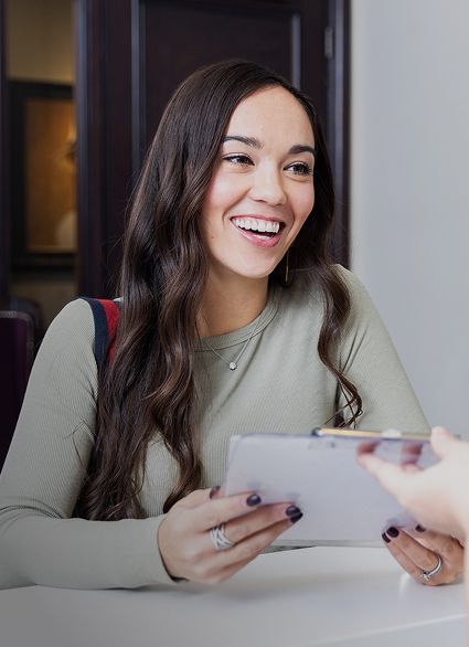 Smiling woman receiving a clipboard at a table.