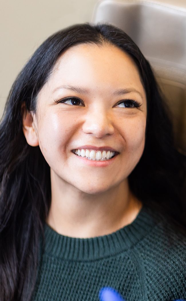 Smiling woman with long, dark hair indoors.