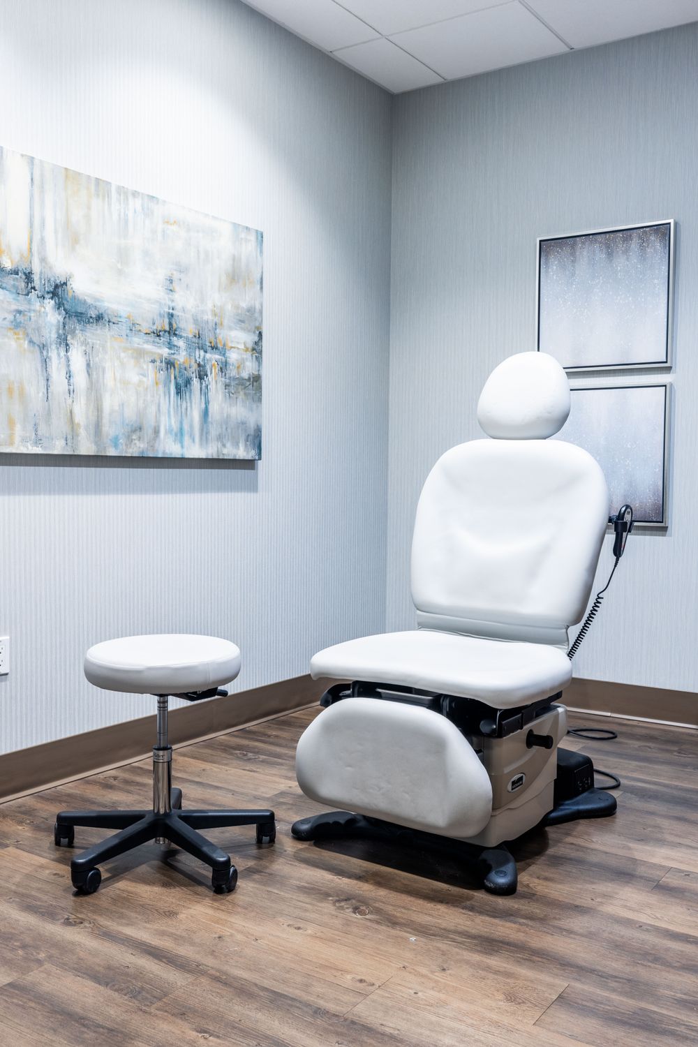 Treatment room with adjustable medical chairs and artwork.
