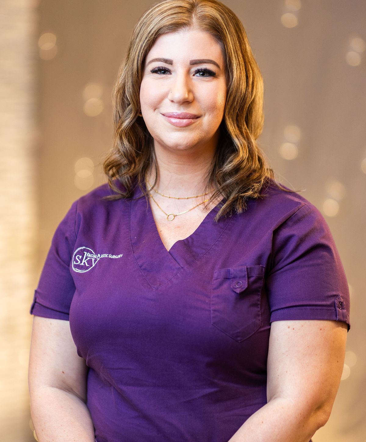Healthcare professional in purple scrubs, smiling.