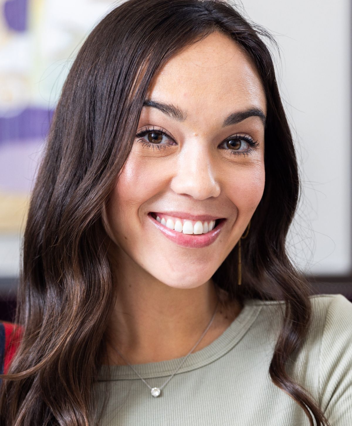 Smiling woman with long dark hair indoors.