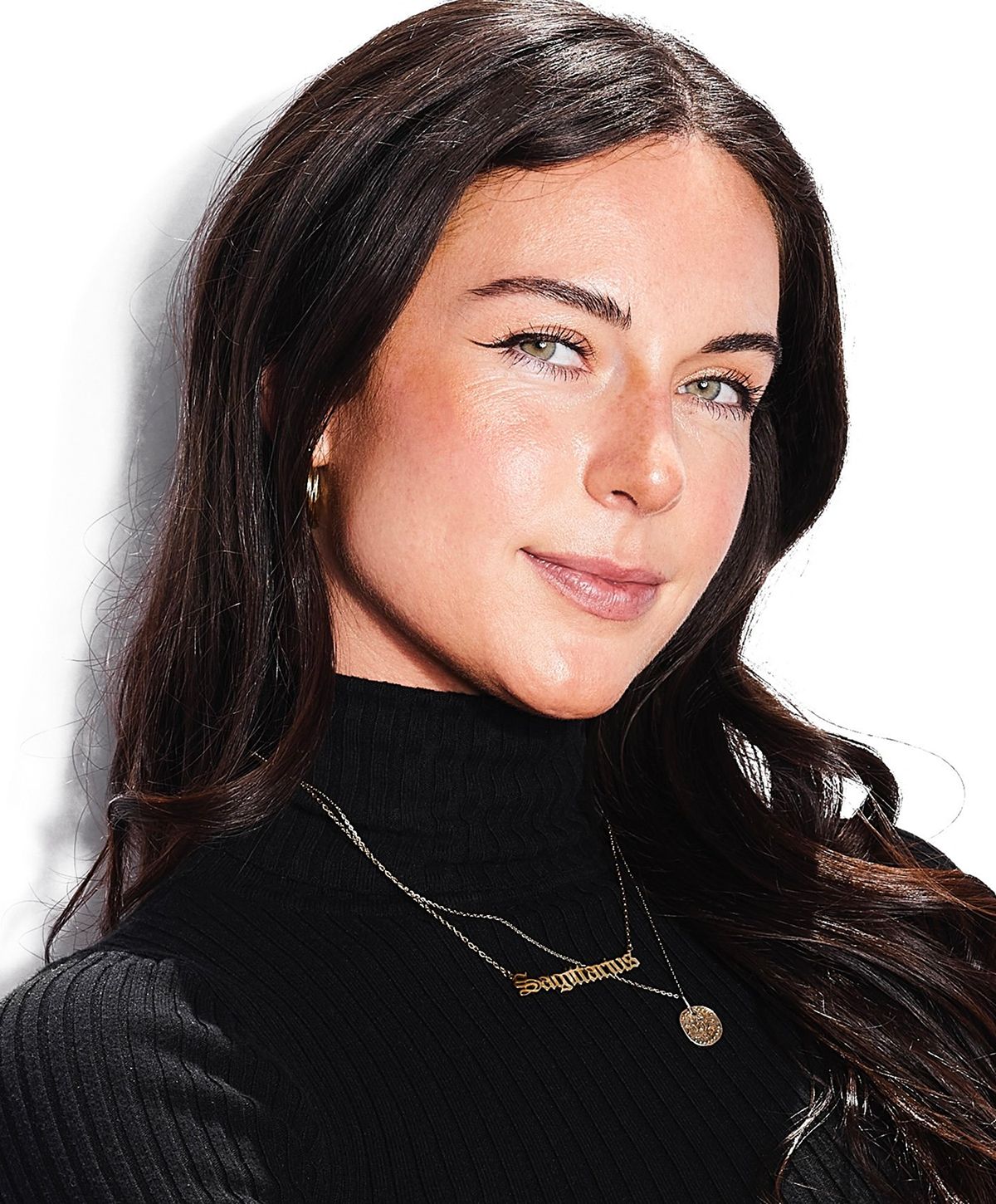 Woman wearing a black turtleneck and jewelry.
