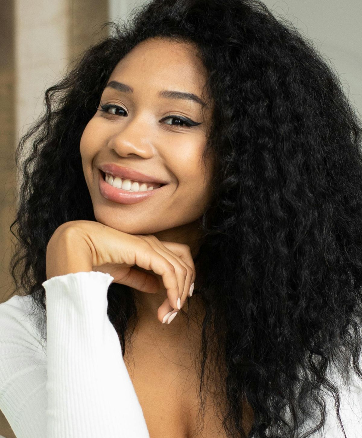 Smiling person with curly hair and white top.
