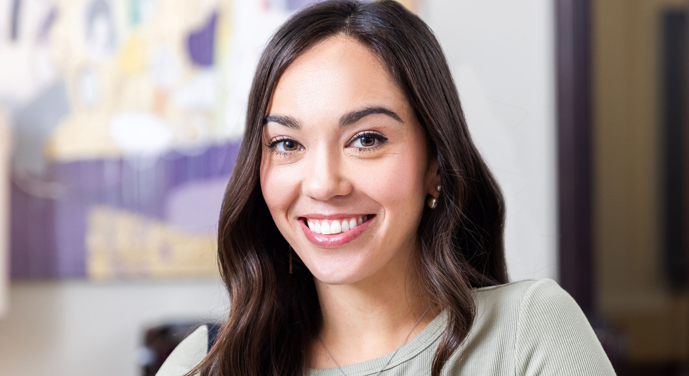 Smiling woman with long hair in soft lighting.