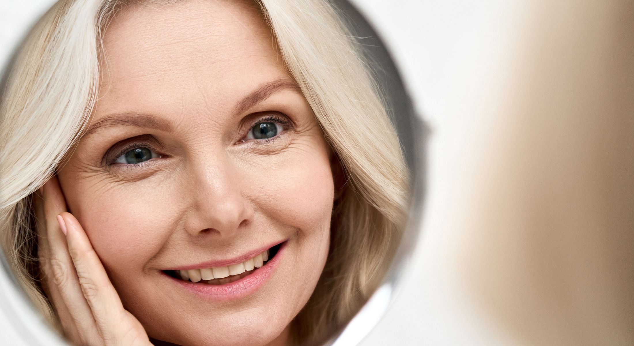 Smiling woman looking in a round mirror.