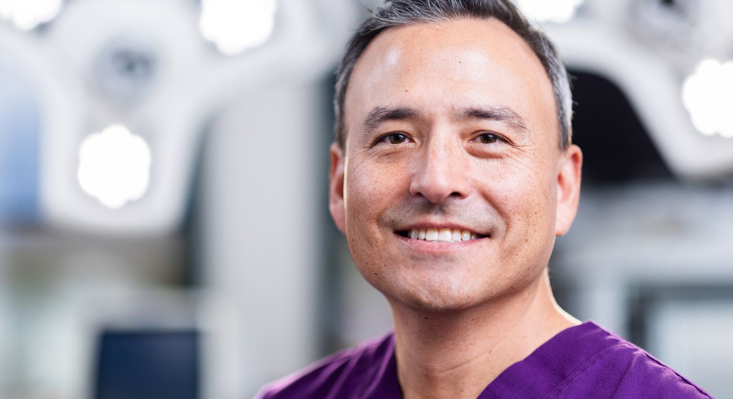 Smiling medical professional in surgical scrubs.